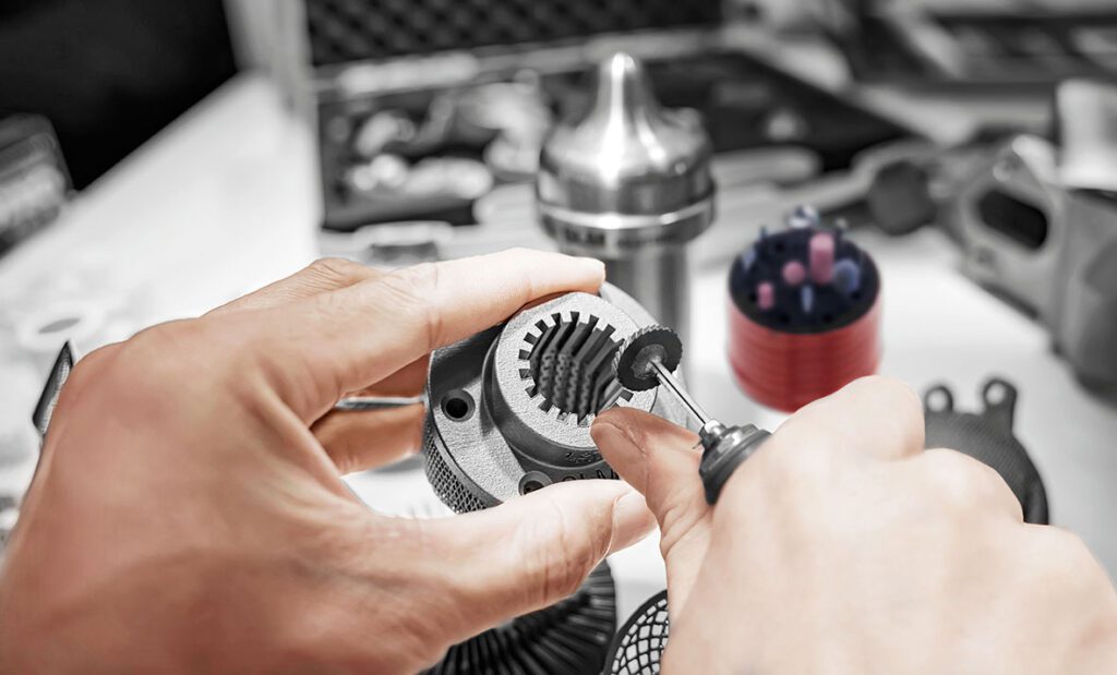 A technician carefully refining the surface of a 3D-printed metal part using a specialized tool, ensuring smooth finishes and high precision in the final product.