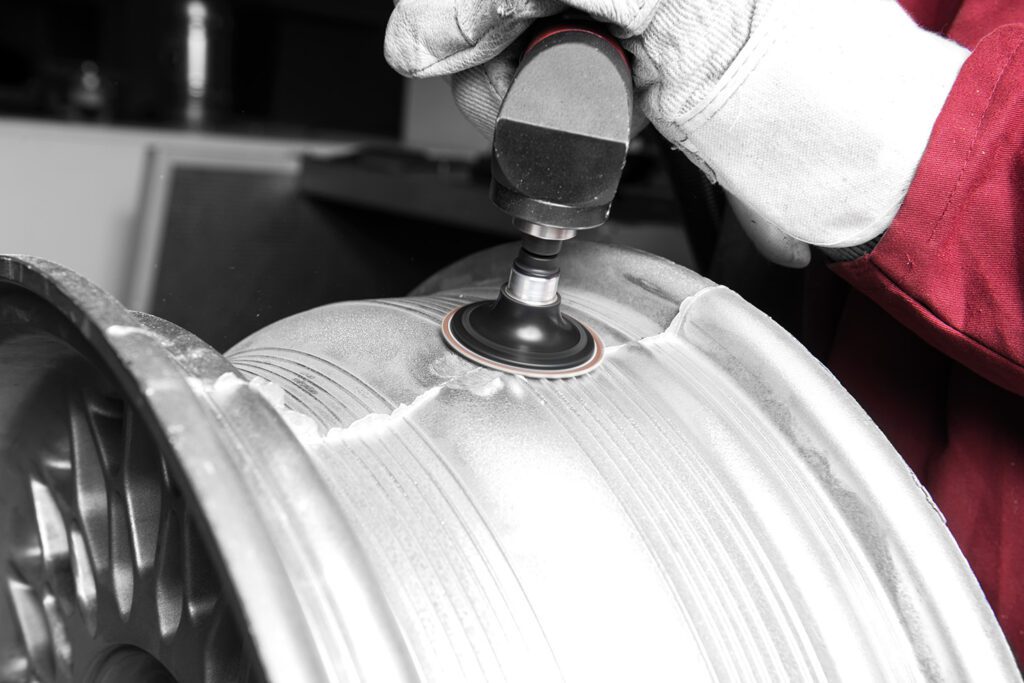 Car rim is processed with a self-clamping abrasive disc.