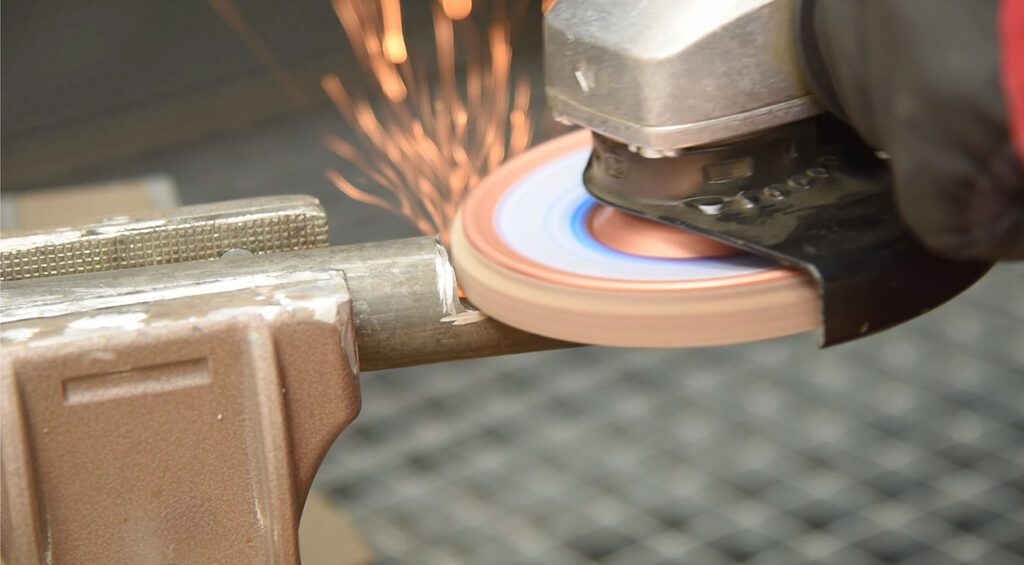 Angle grinder with SLTT disc produces sparks while grinding steel.